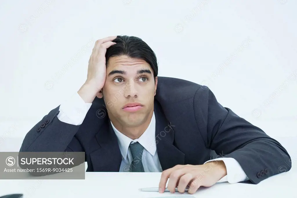 Young businessman slouching on desk, holding head