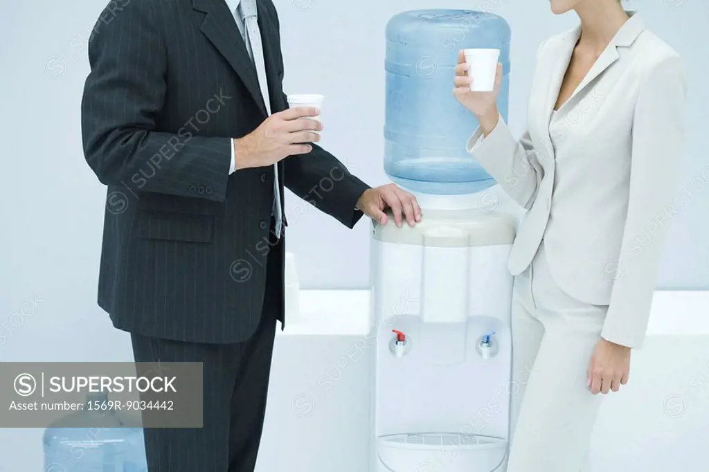 Two business colleagues standing by water cooler, cropped