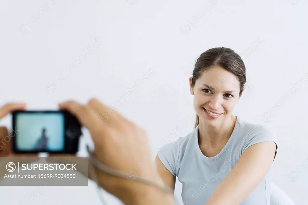Woman posing in front of digital camera, smiling