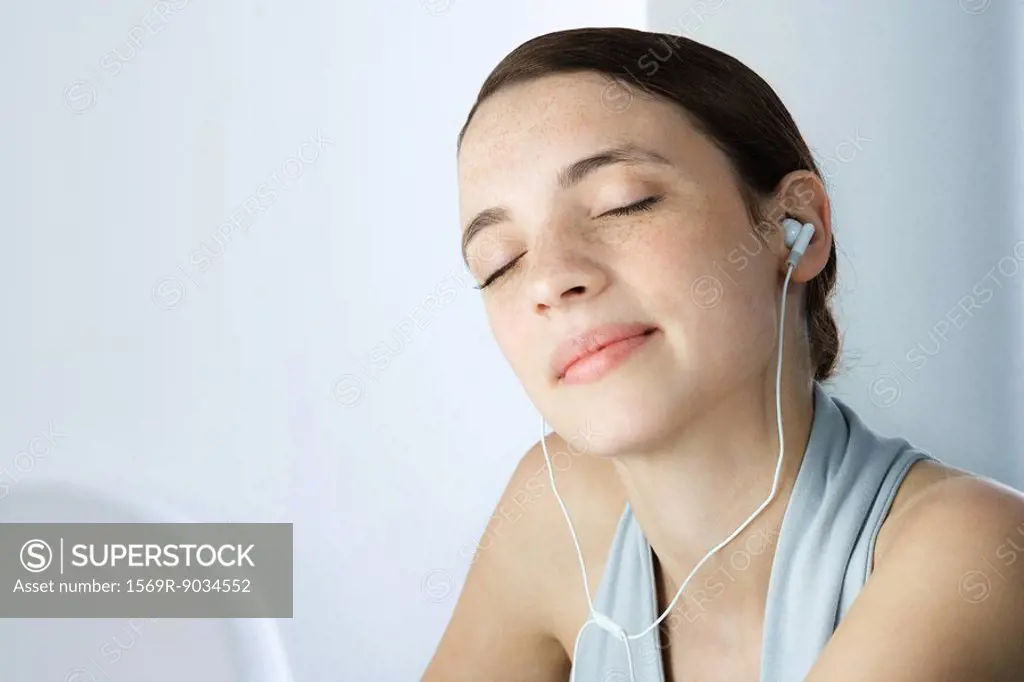 Young woman listening to earphones, eyes closed