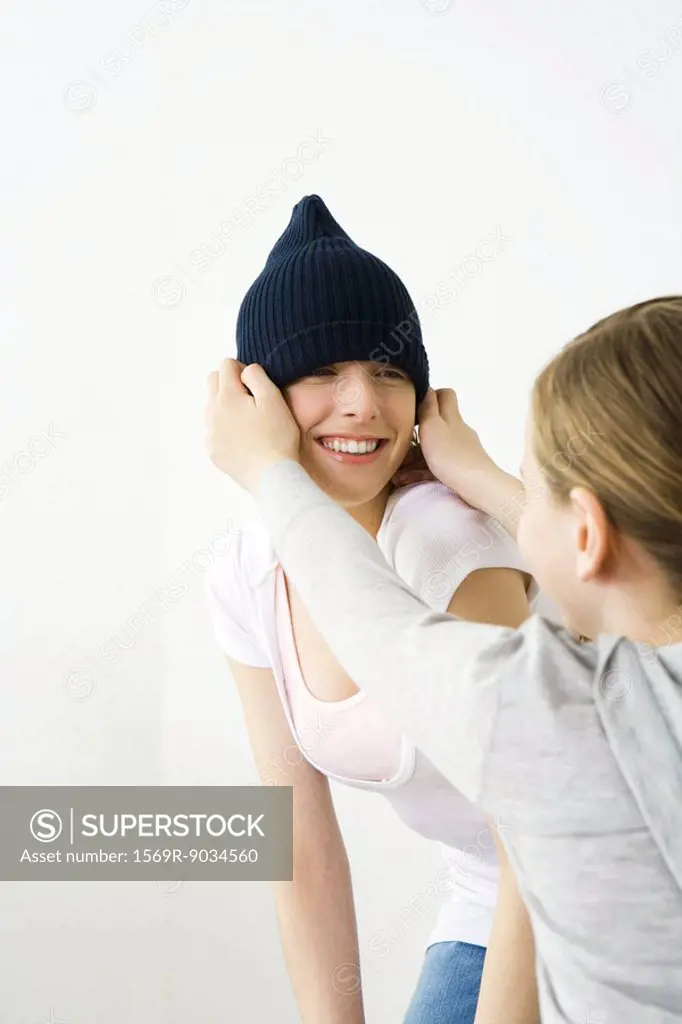 Girl pulling knit hat over her friend´s head