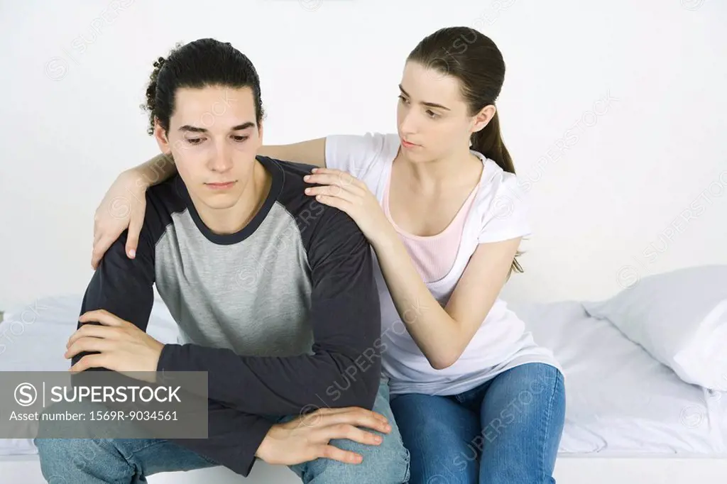Young couple together on bed, female´s arm around male´s shoulder