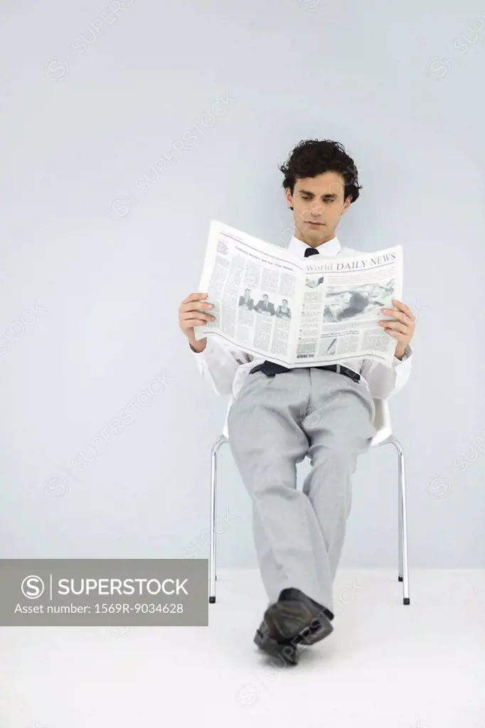 Businessman slouching in chair, reading newspaper