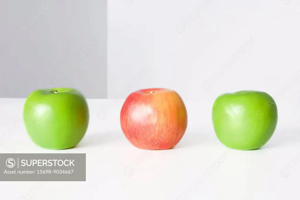 Three apples in a row, two green and one red, close-up