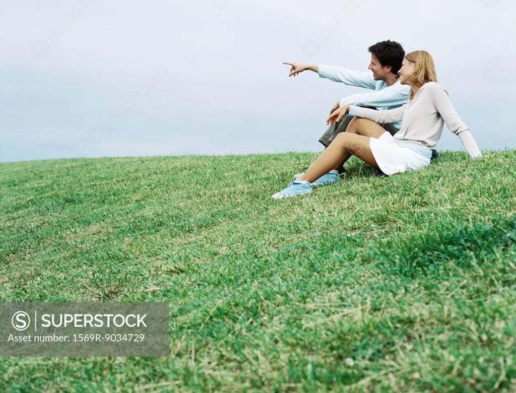 Couple sitting on grass, looking toward distance