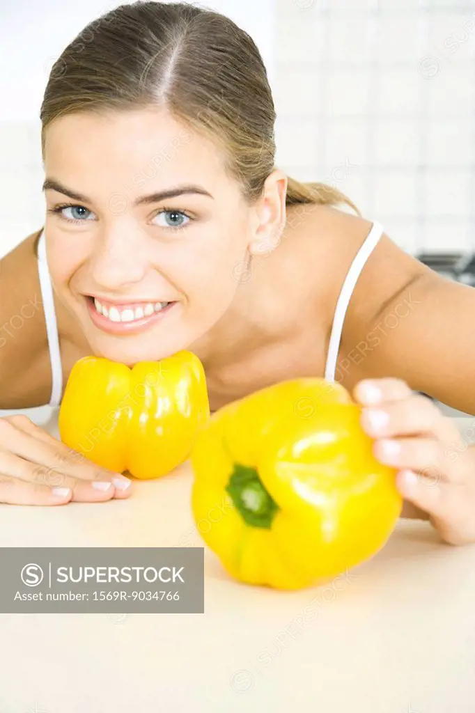 Young woman posing with yellow bell peppers