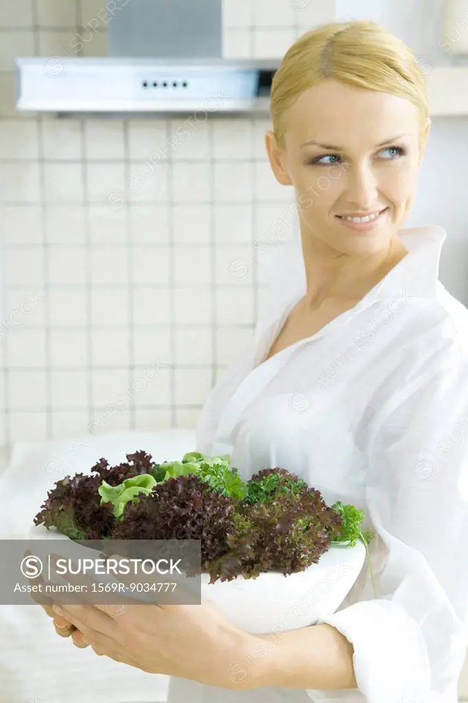 Woman holding bowl full of different lettuces