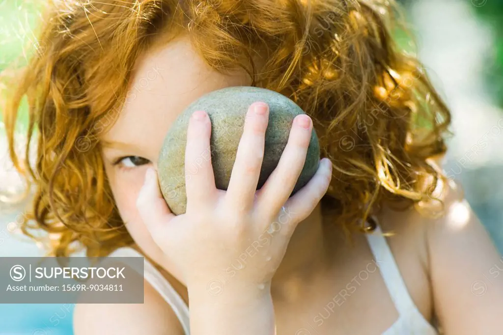 Girl holding up stone to face