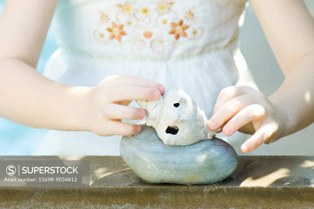 Girl stacking seashell on stone