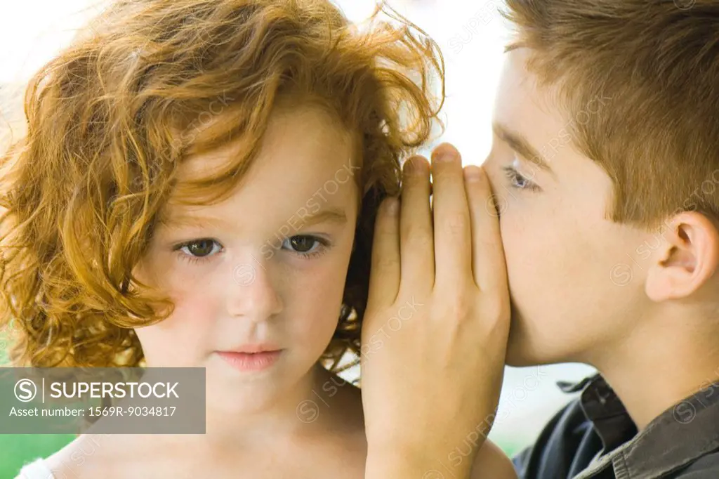 Boy whispering into girl´s ear, close-up