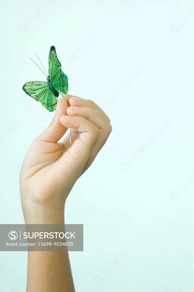Child´s hand holding fake butterfly