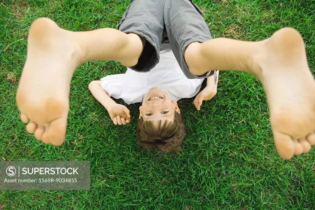 Boy lying on grass with legs in air, overhead view