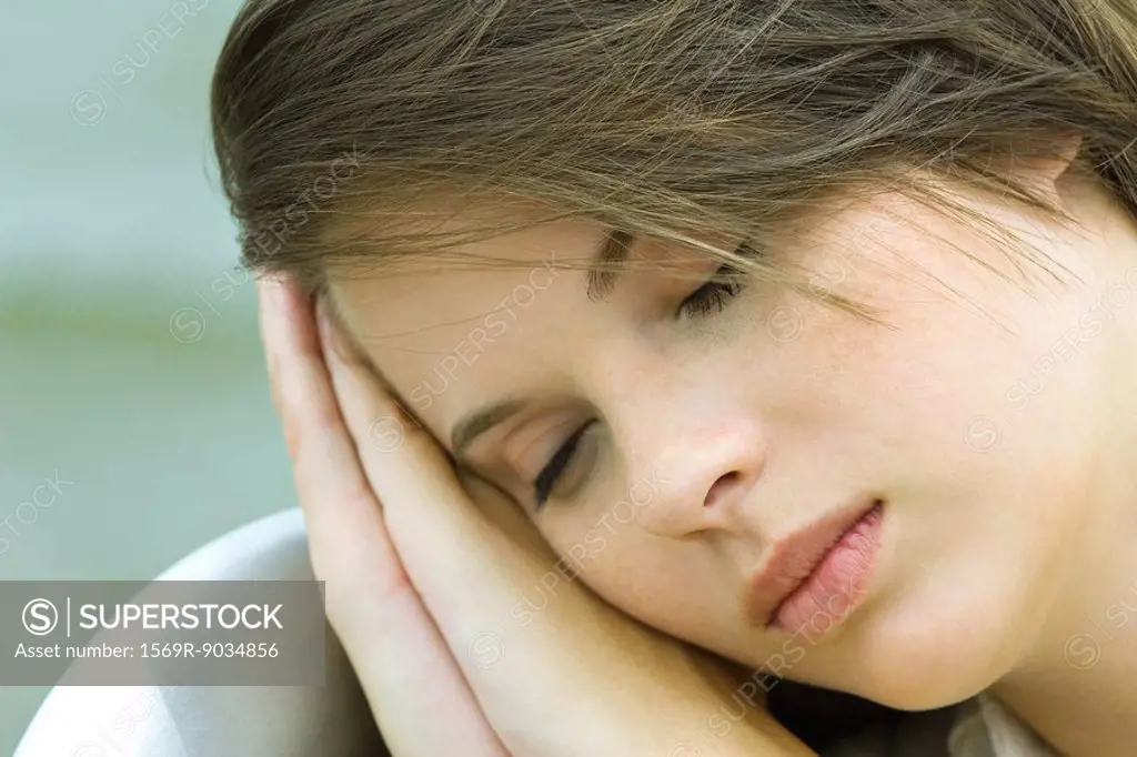 Teenage girl resting head on hands, close-up