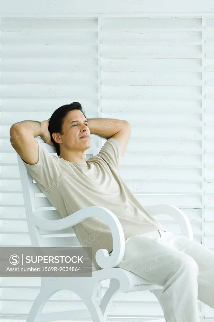 Man sitting on bench, hands behind head, relaxing