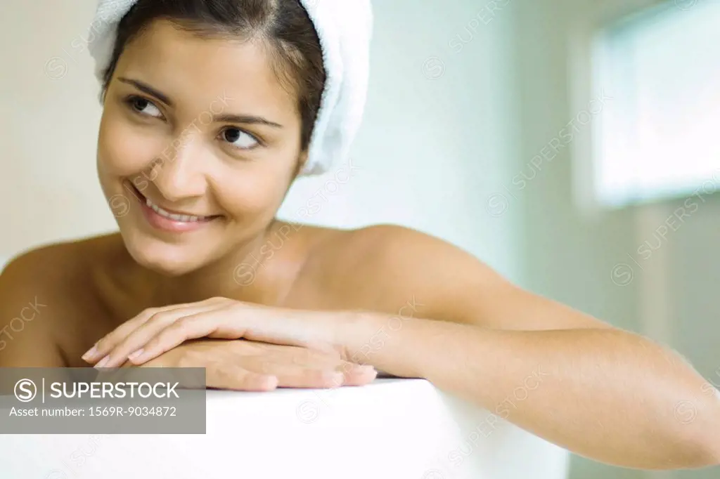 Woman in bathtub, wearing shower cap, smiling