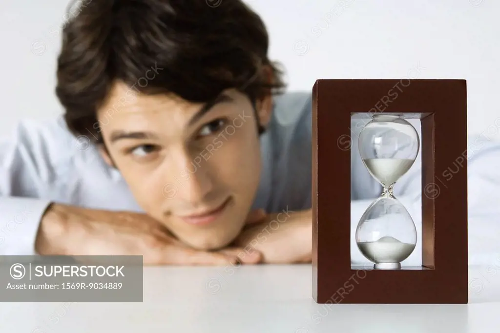 Man looking at hourglass, head resting on hands