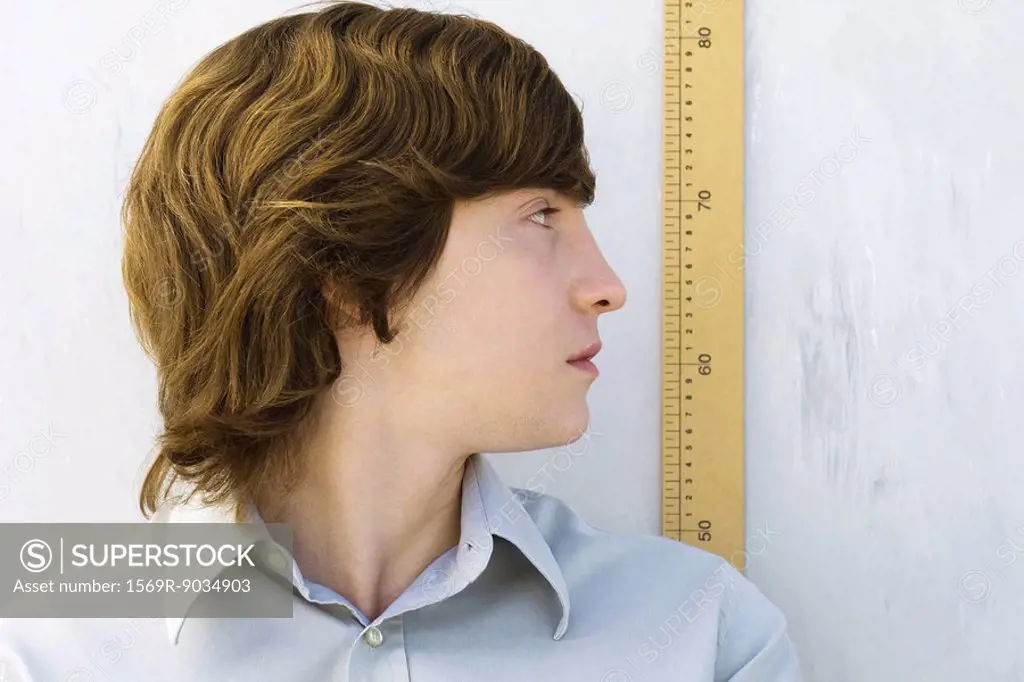 Young man looking over shoulder at yardstick, close-up
