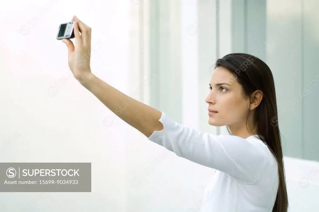 Woman photographing herself with photophone, arm raised