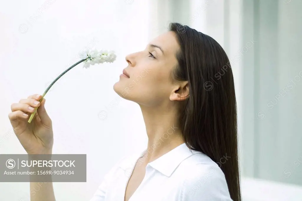 Woman smelling flower, head back, side view