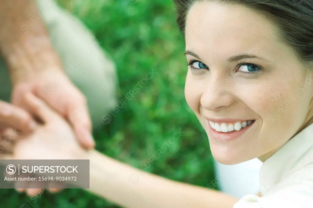 Teen girl holding man´s hand, smiling over shoulder at camera, cropped view