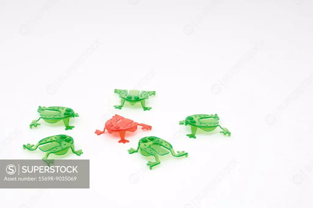 Green plastic frogs surrounding red frog in center
