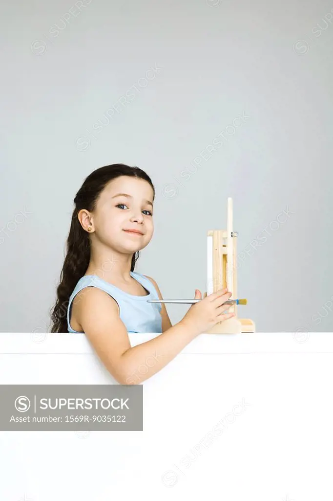 Little girl with small easel, smiling at camera