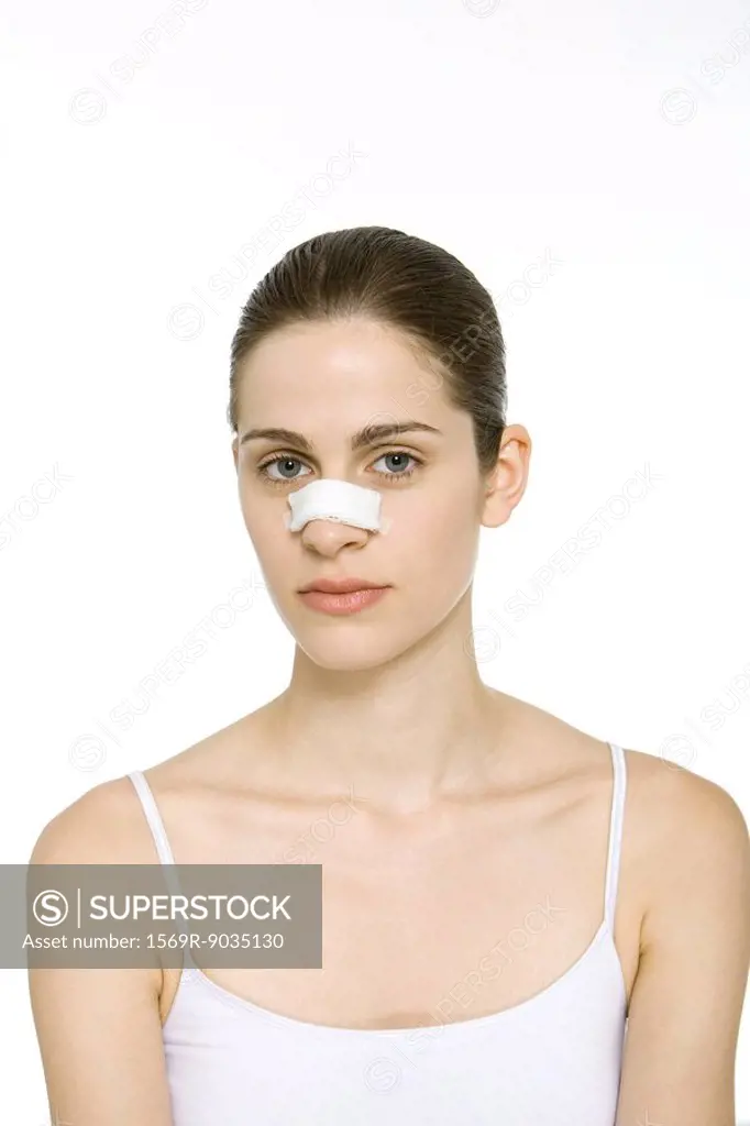 Young woman with bandage on nose, looking at camera, portrait