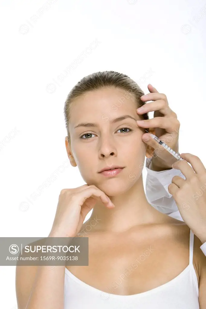 Young woman receiving botox injection, looking at camera