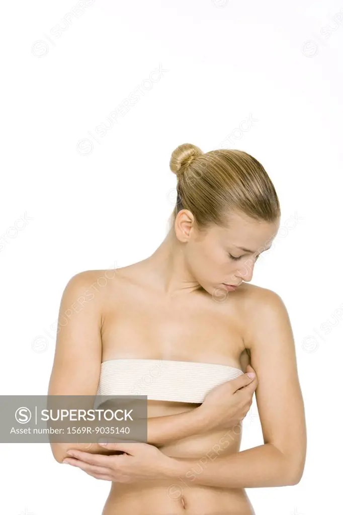Woman holding bandage across breasts, head down