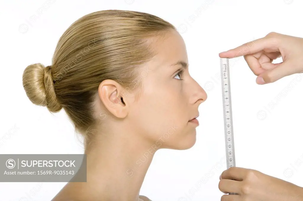 Woman in profile, face being measured by ruler