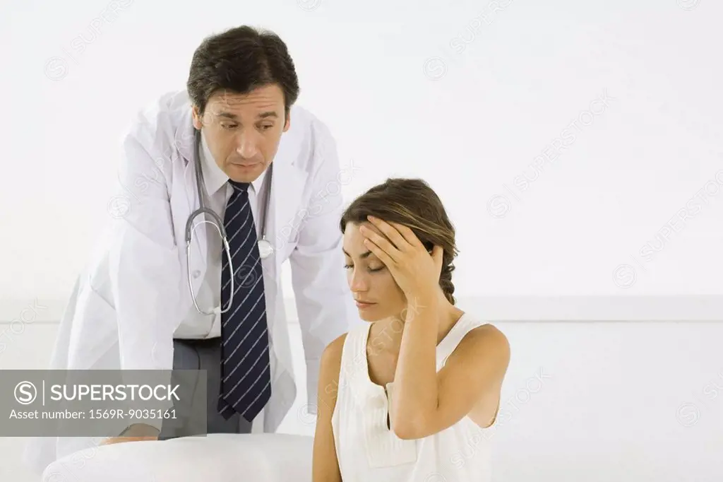Woman holding head, doctor leaning behind her