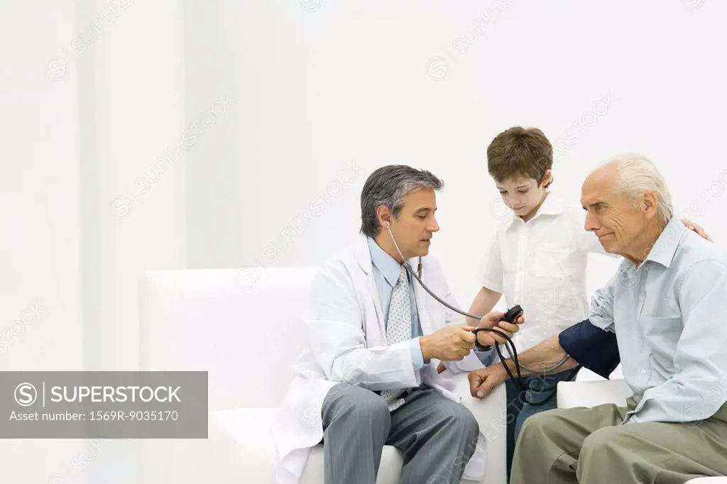 Doctor measuring elderly man´s blood pressure, boy watching