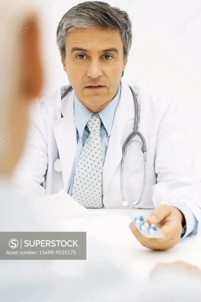 Doctor giving patient prescription drugs, over the shoulder view, cropped