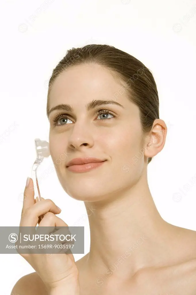 Woman rollerball wand on cheek, smiling