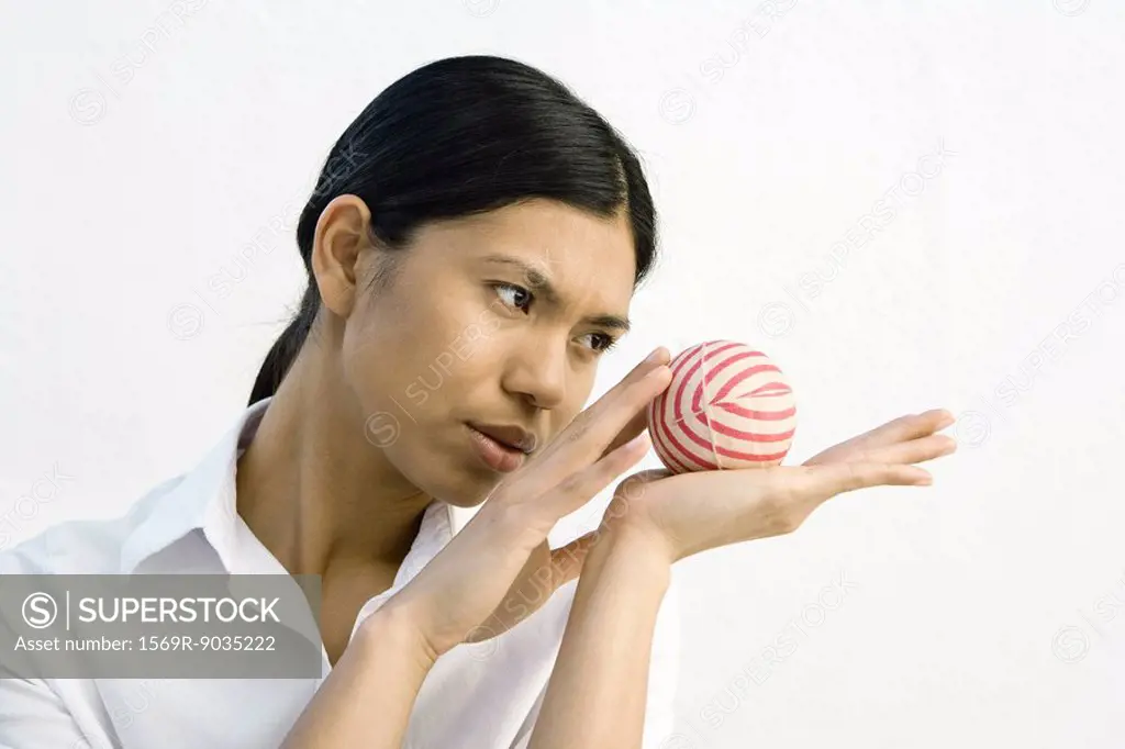 Woman holding striped ball in open palm, looking away