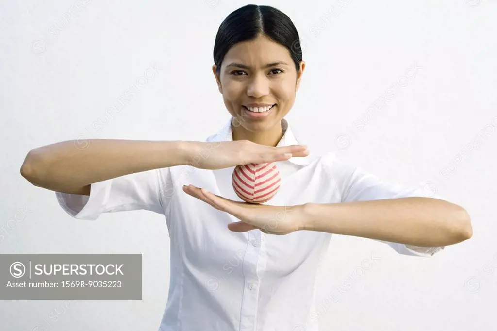 Woman balancing ball between her hands, smiling at camera