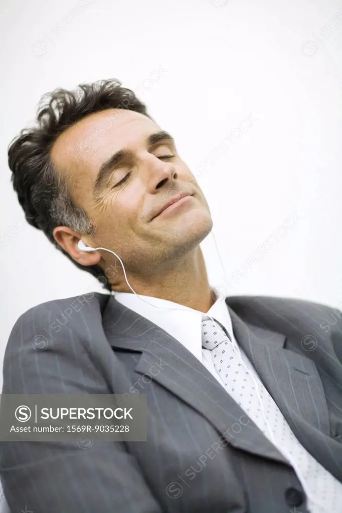Businessman listening to earphones, eyes closed