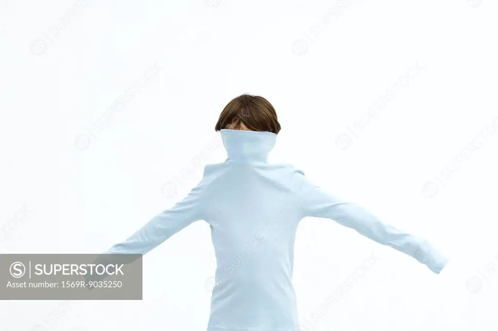 Boy wearing turtleneck pulled over his face, arms outstretched