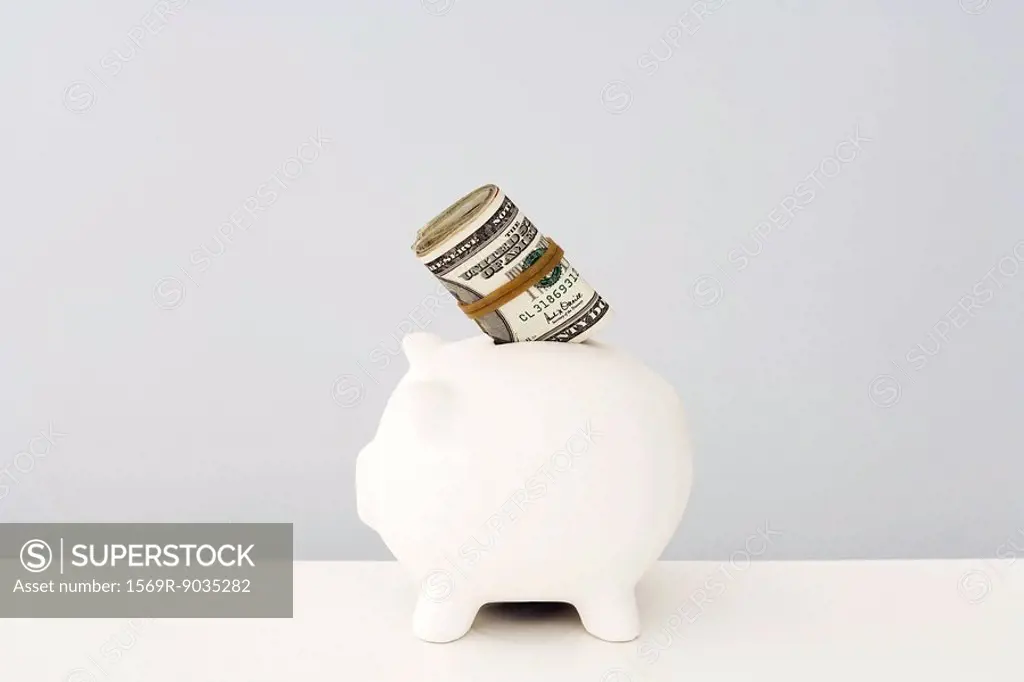 Piggy bank with wad of money sticking out
