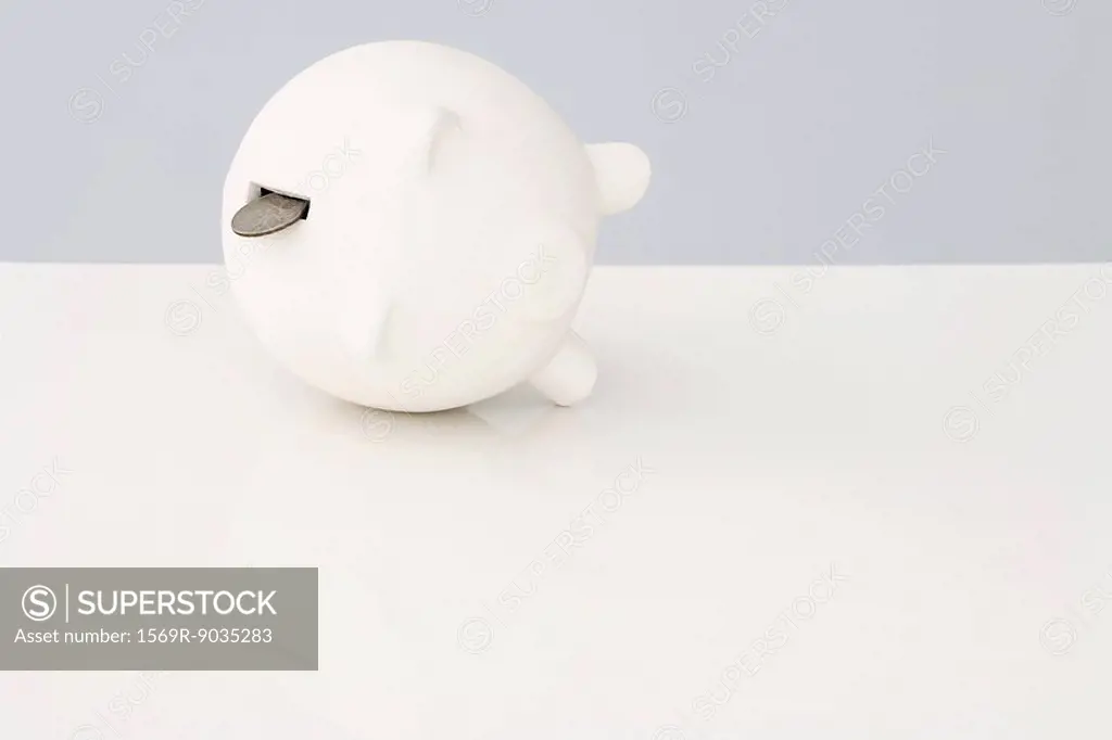 Piggy bank on its side with a coin falling out