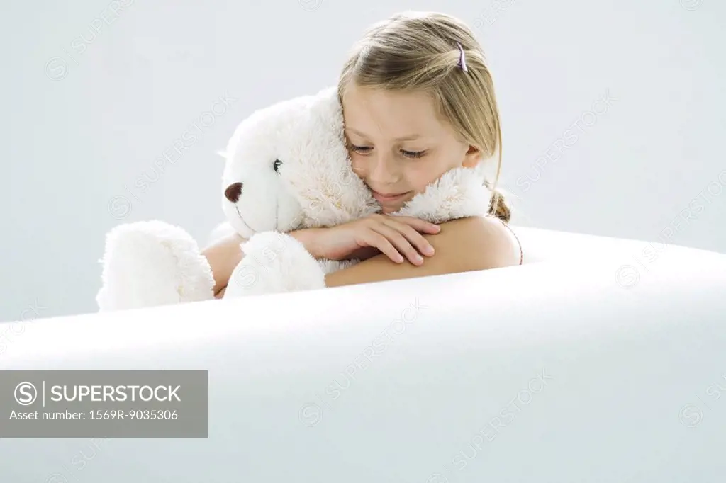 Girl holding teddy bear, smiling, looking down