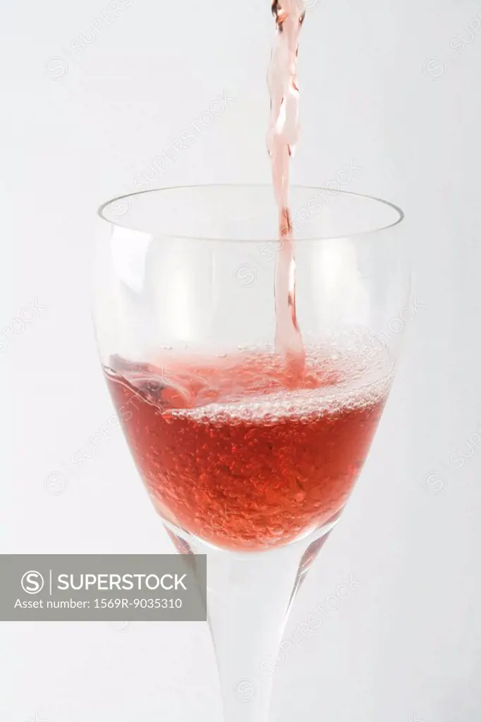 Rose wine pouring into glass, close-up