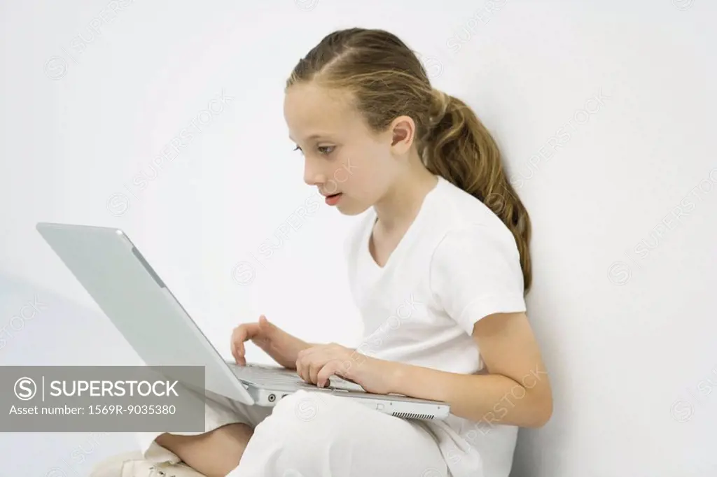 Little girl using laptop computer, side view