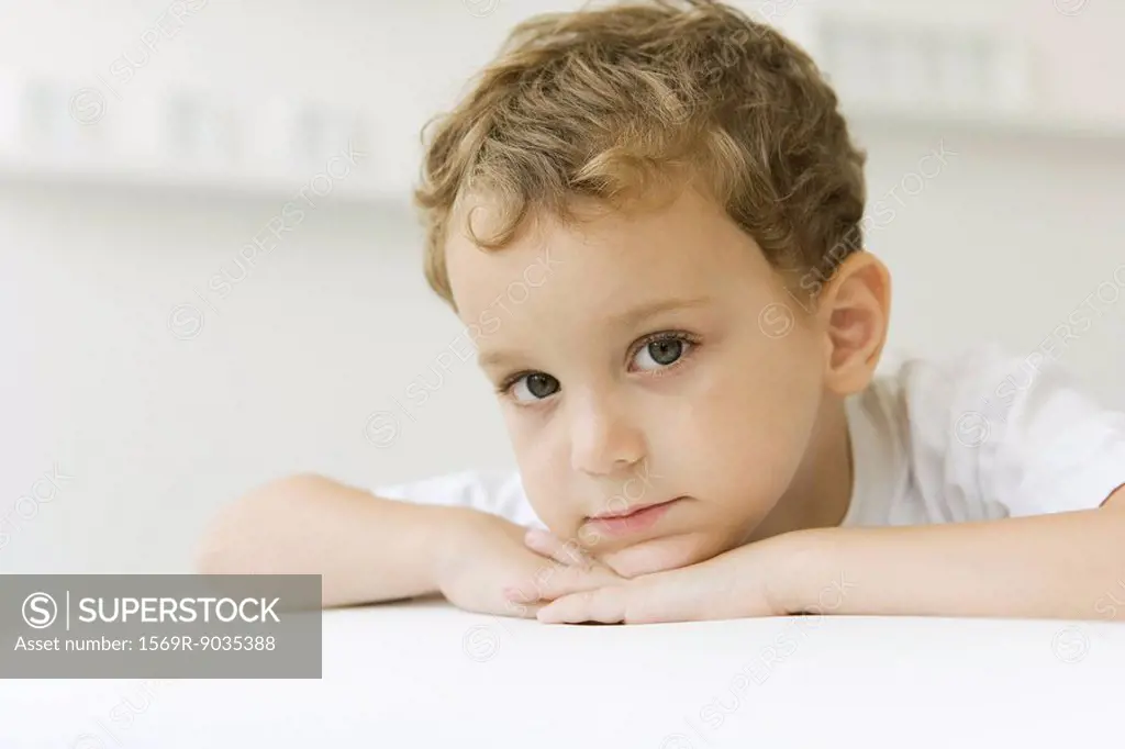 Little boy looking at camera, head resting on arms, portrait