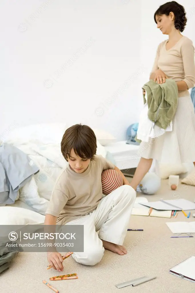 Mother helping boy clean messy room