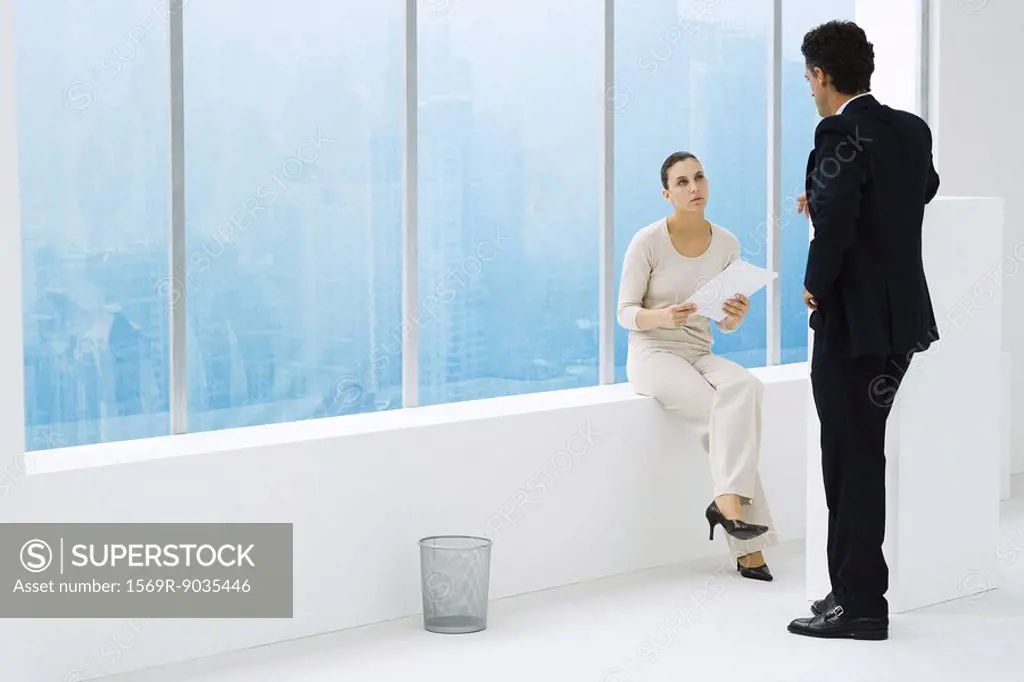 Two business associates by window, having conversation