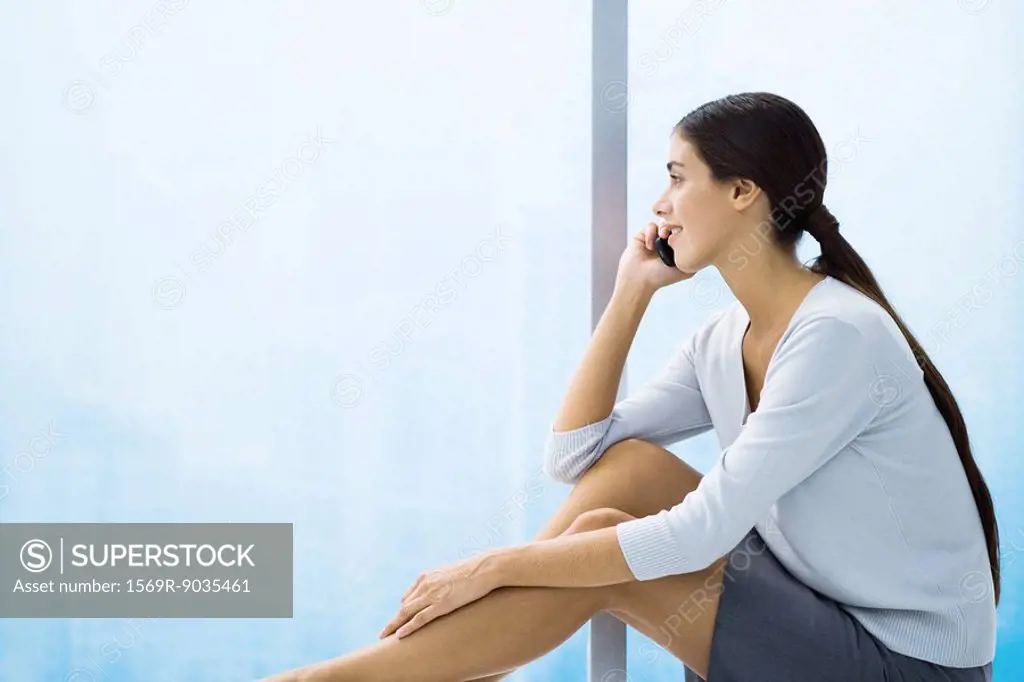 Woman talking on cell phone, looking out window, sitting