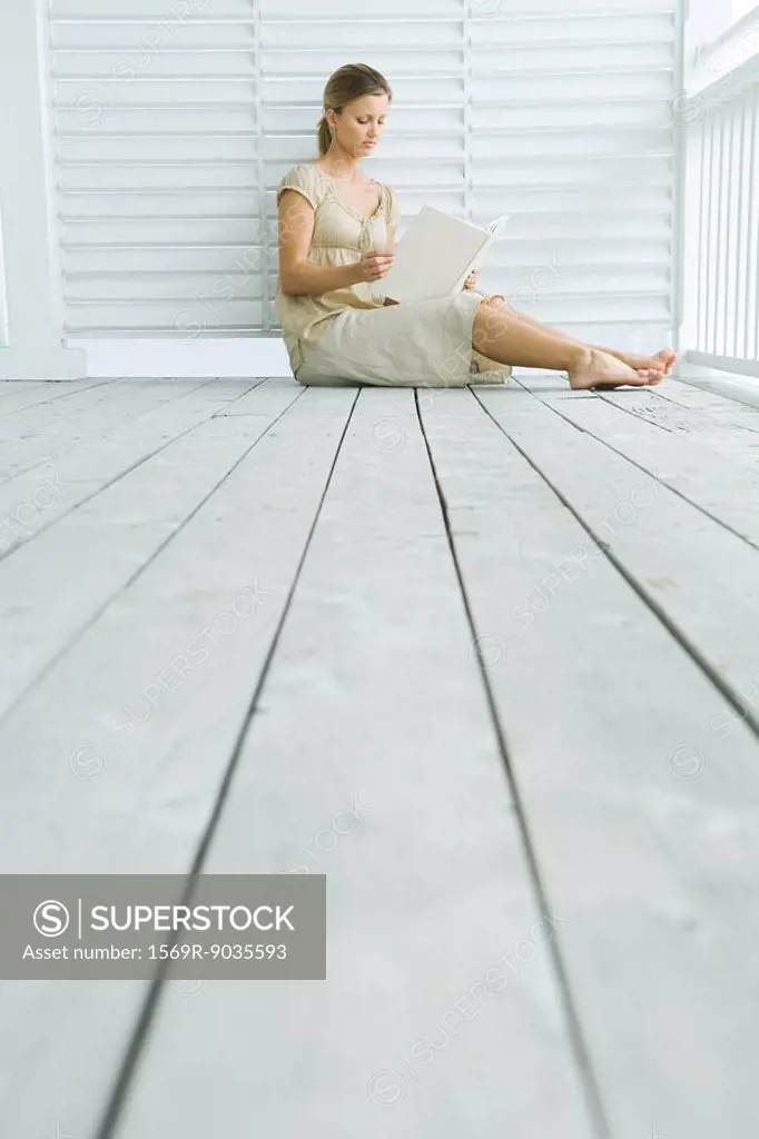 Woman sitting on porch reading book, low angle view