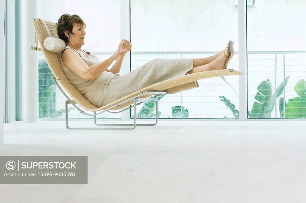 Woman reclining on lounge chair, side view