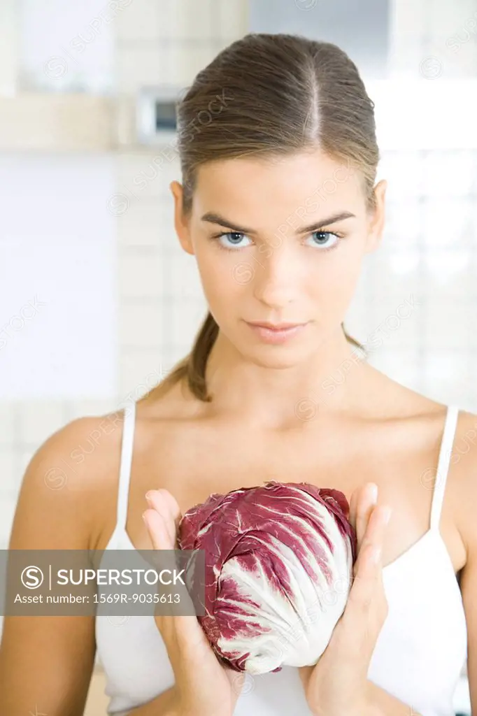Young woman holding head of chicory, looking at camera